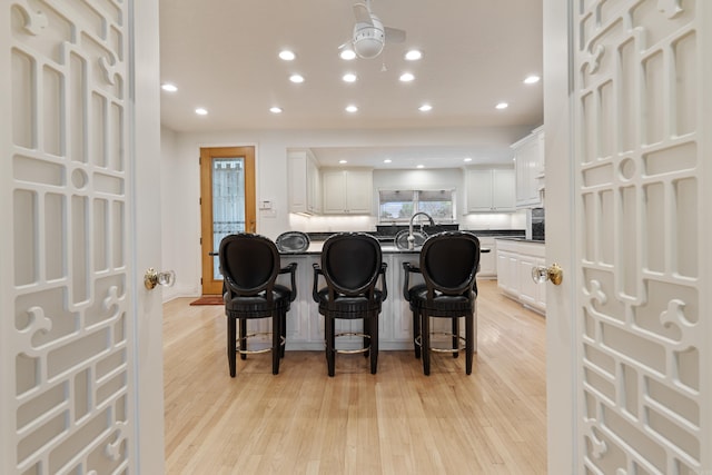 5000 Central Ave Unit 26-27, Hot Springs, AR 71913 - kitchen featuring dark countertops, a kitchen bar, light wood-style flooring, white cabinetry, and recessed lighting