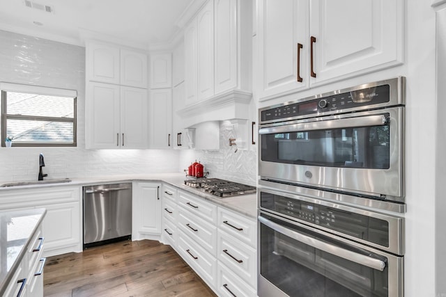17 Cove Creek Pt, Little Rock, AR 72211 - kitchen with stainless steel appliances, a sink, white cabinetry, backsplash, and dark wood-style flooring