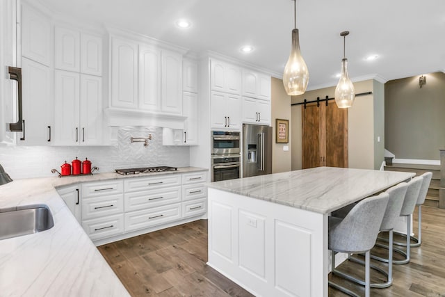 17 Cove Creek Pt, Little Rock, AR 72211 - kitchen featuring stainless steel appliances, a barn door, tasteful backsplash, dark wood-style floors, and a kitchen island