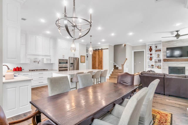 17 Cove Creek Pt, Little Rock, AR 72211 - dining space with a barn door, a chandelier, recessed lighting, light wood-style flooring, and crown molding