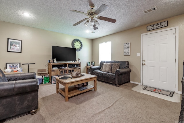 living area with a ceiling fan, carpet flooring, and a textured ceiling
