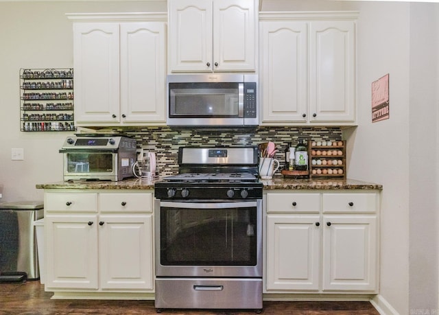 51 Waters Edge Dr, Little Rock, AR 72204 - kitchen with appliances with stainless steel finishes, dark stone countertops, white cabinetry, backsplash, and dark wood-style floors