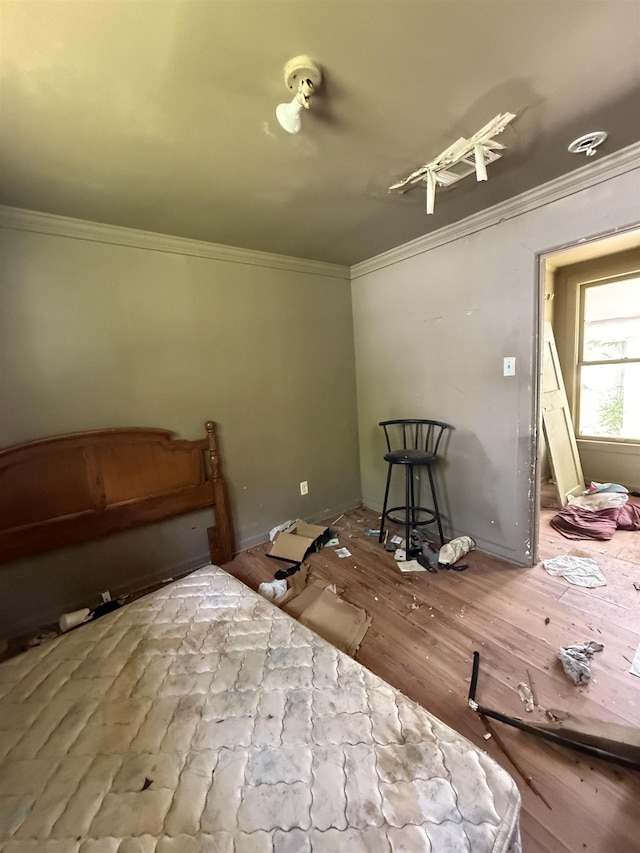 bedroom with ornamental molding and wood finished floors