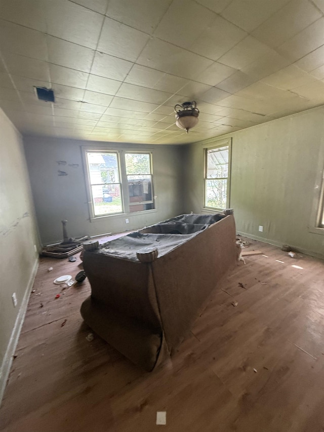 bedroom with wood finished floors, multiple windows, and baseboards