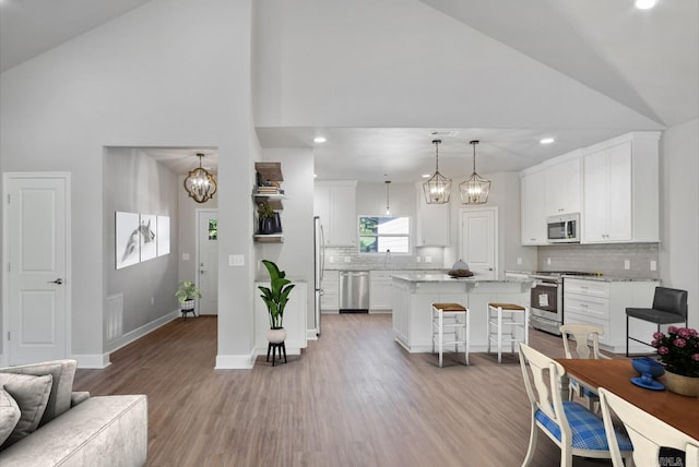 32 Propio Way, Hot Springs Village, AR 71909 - kitchen with stainless steel appliances, high vaulted ceiling, a chandelier, light wood-style flooring, and a kitchen breakfast bar