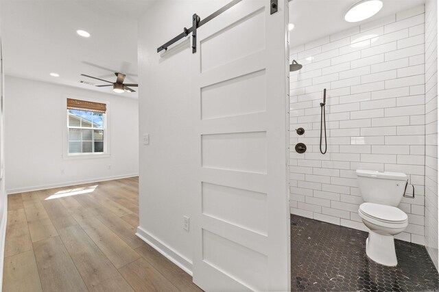 bathroom with toilet, ceiling fan, tiled shower, recessed lighting, and wood finished floors