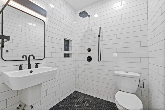 bathroom featuring tile walls, a tile shower, and toilet