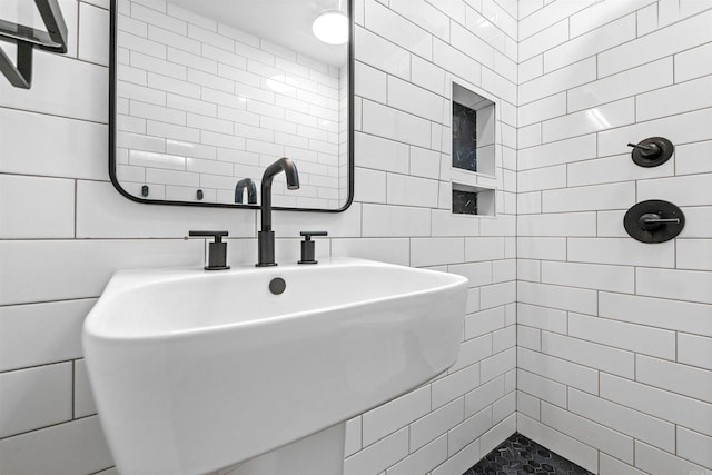 full bathroom with a sink, a tile shower, and tile walls