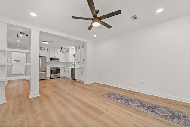 unfurnished living room with ceiling fan, a sink, light wood finished floors, recessed lighting, and baseboards