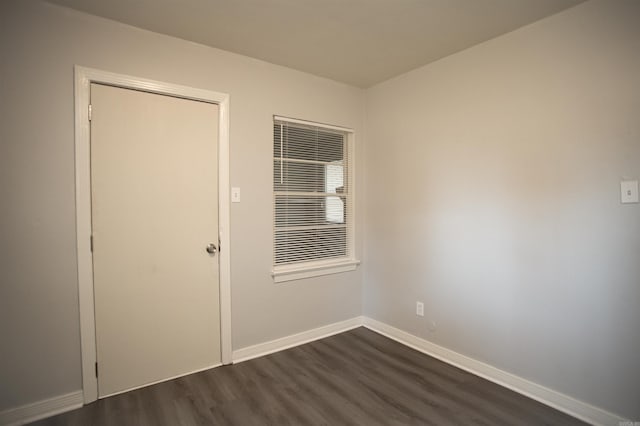 spare room featuring dark wood-type flooring and baseboards