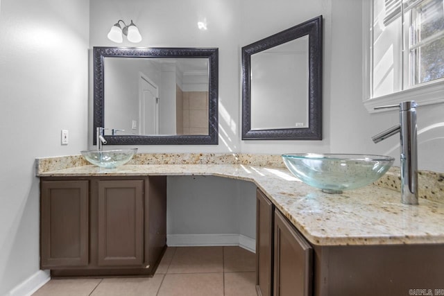 bathroom with double vanity, tile patterned floors, and baseboards