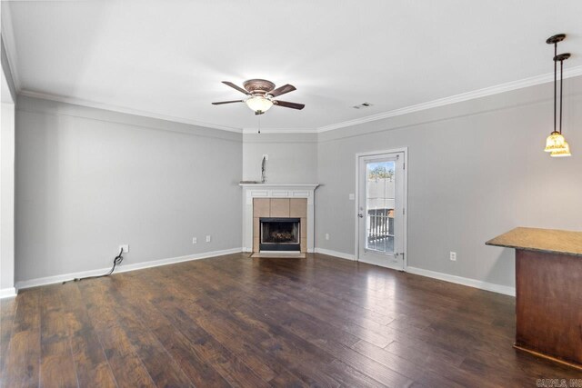 unfurnished living room with ceiling fan, crown molding, a tile fireplace, dark wood-type flooring, and baseboards