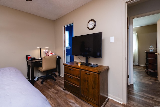 bedroom with dark wood-style floors, baseboards, an office area, and a textured ceiling