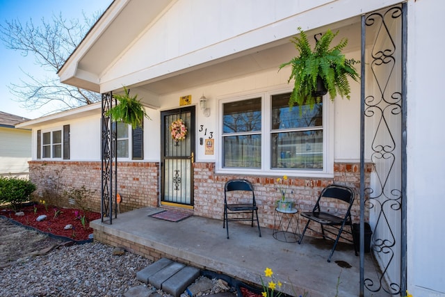entrance to property with covered porch and brick siding