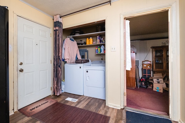 clothes washing area with washer and dryer, wood finished floors, crown molding, and a textured ceiling