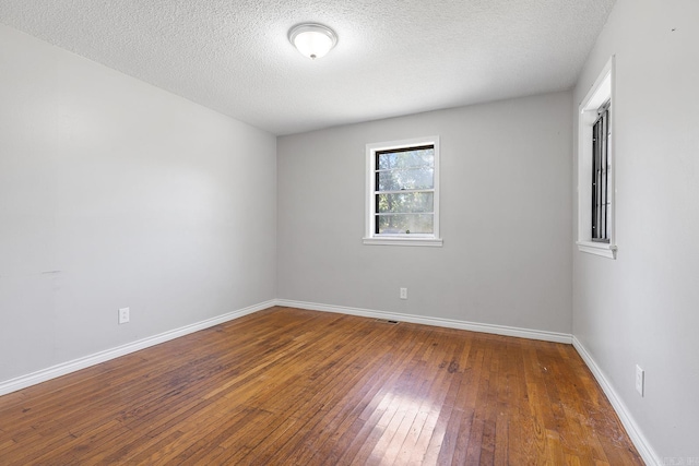 spare room with hardwood / wood-style flooring, baseboards, and a textured ceiling