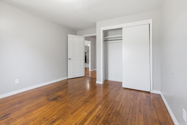 unfurnished bedroom featuring hardwood / wood-style floors, a closet, baseboards, and a textured ceiling