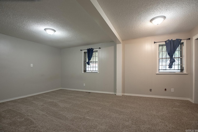 spare room with a textured ceiling, carpet floors, and baseboards