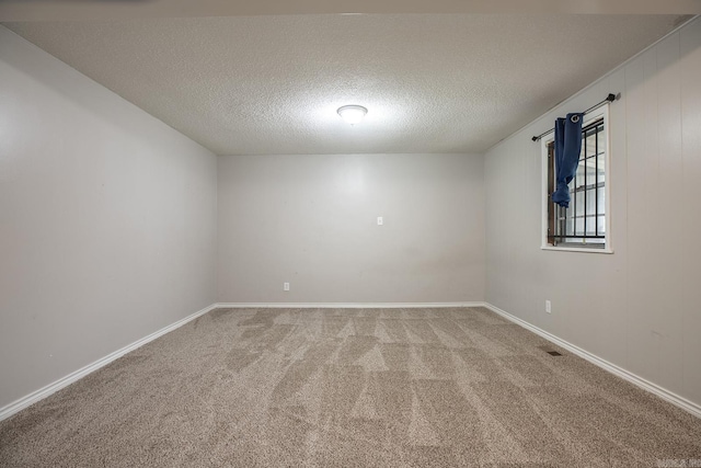 empty room featuring light colored carpet, a textured ceiling, and baseboards