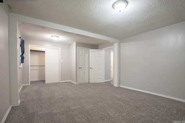 carpeted spare room featuring a textured ceiling and baseboards