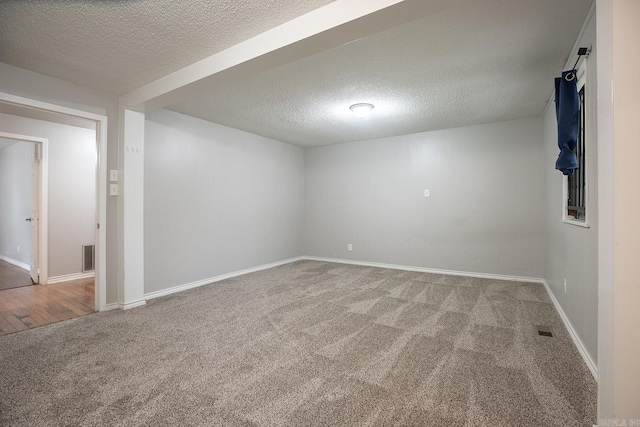 carpeted spare room featuring a textured ceiling and baseboards