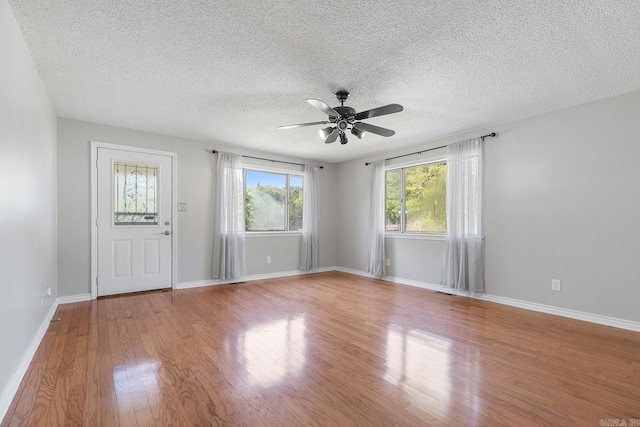 foyer entrance with a ceiling fan, wood finished floors, a textured ceiling, and baseboards