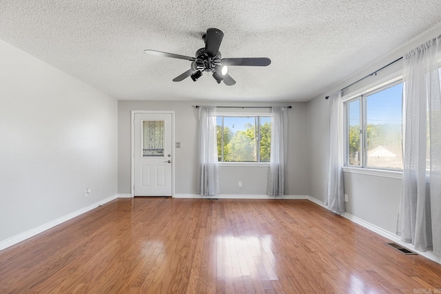 unfurnished room featuring wood finished floors, a textured ceiling, a ceiling fan, and baseboards