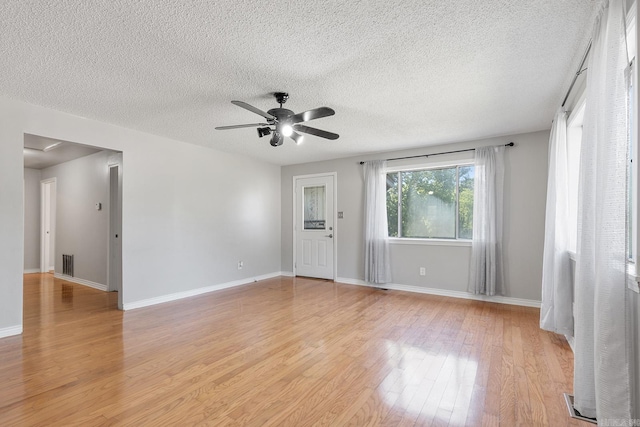 spare room with ceiling fan, light wood-style floors, a textured ceiling, and baseboards