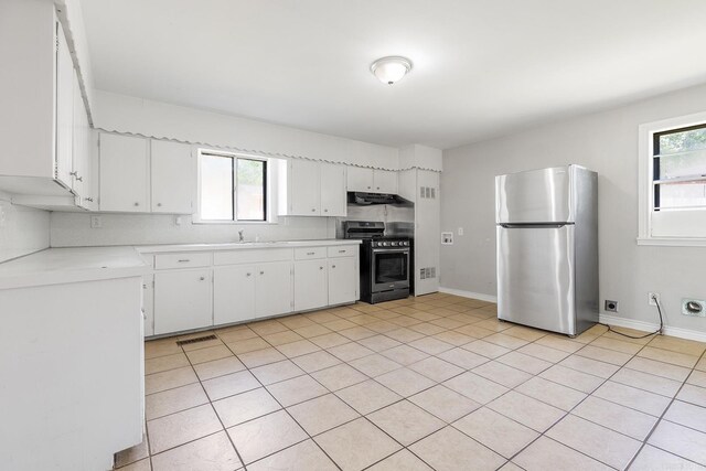 kitchen featuring appliances with stainless steel finishes, light countertops, under cabinet range hood, white cabinets, and light tile patterned floors
