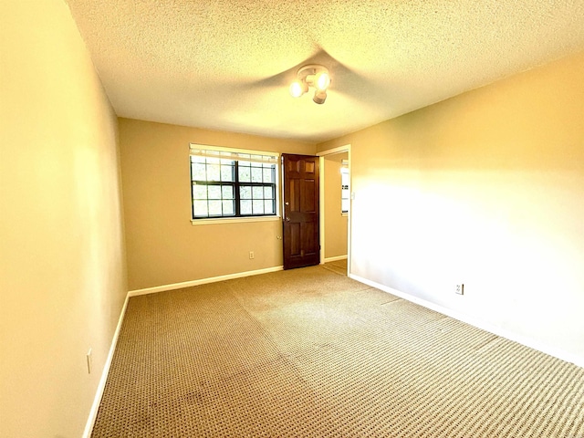 unfurnished room with light colored carpet, baseboards, and a textured ceiling