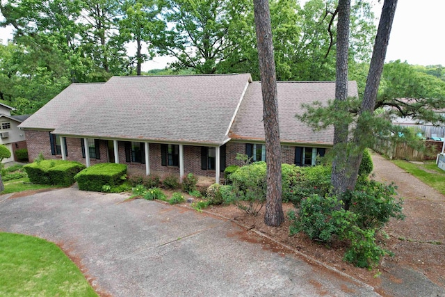 view of front facade featuring brick siding, roof with shingles, and fence
