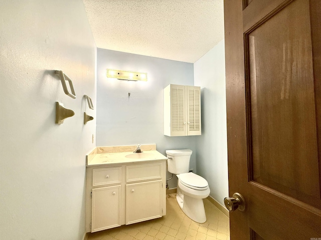 bathroom with toilet, a textured ceiling, vanity, tile patterned flooring, and baseboards