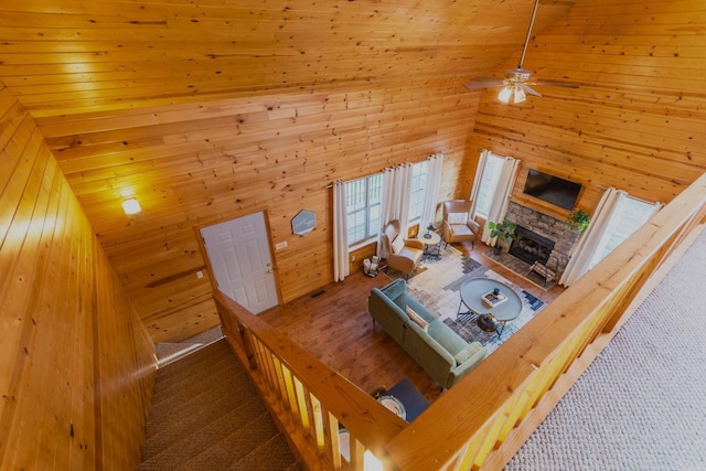 221 Skyline Dr, Greers Ferry, AR 72067 - carpeted living area with wooden walls, a ceiling fan, a stone fireplace, wood ceiling, and high vaulted ceiling