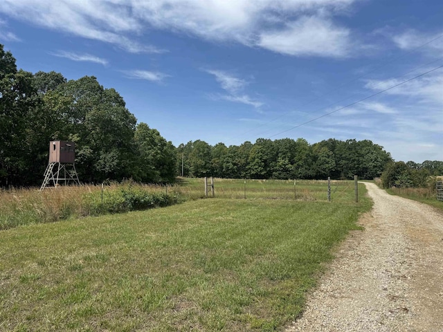 view of grassy yard with a rural view and a wooded view
