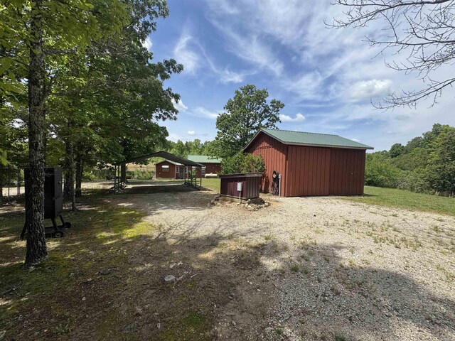 view of shed with a carport and gravel driveway