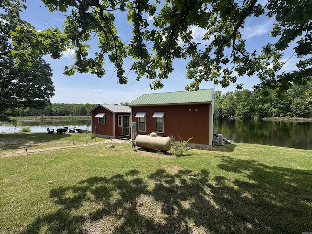 view of green lawn featuring a water view and entry steps
