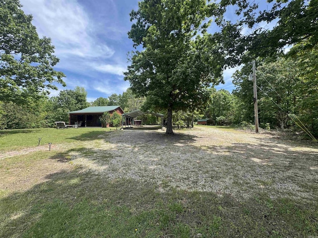 view of green lawn with a detached carport, a pole building, and an outdoor structure