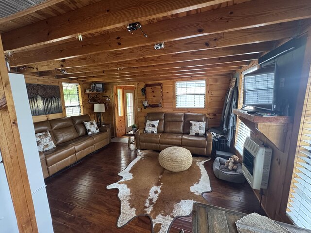 living area featuring hardwood / wood-style flooring, beam ceiling, heating unit, healthy amount of natural light, and wooden walls