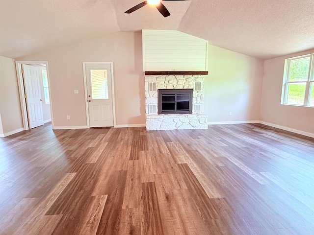 4090 Ar 56th Hwy, Wideman, AR 72585 - unfurnished living room featuring lofted ceiling, ceiling fan, wood finished floors, a stone fireplace, and a textured ceiling
