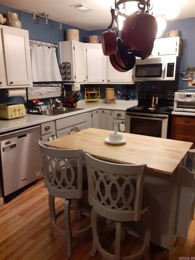 49 Tram, Perryville, AR 72126 - kitchen with appliances with stainless steel finishes, a sink, light wood finished floors, white cabinetry, and a kitchen bar