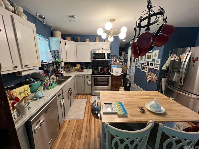 49 Tram, Perryville, AR 72126 - kitchen with stainless steel appliances, light wood-style floors, white cabinets, a chandelier, and pendant lighting