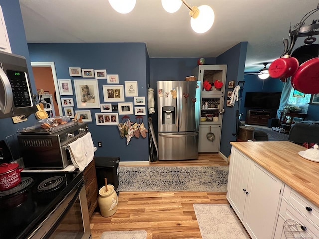 49 Tram, Perryville, AR 72126 - kitchen featuring appliances with stainless steel finishes, butcher block countertops, light wood finished floors, ceiling fan, and white cabinetry