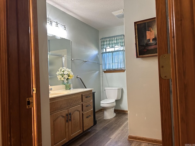 7613 Toltec Dr, North Little Rock, AR 72116 - bathroom featuring a textured ceiling, wood finished floors, toilet, vanity, and a shower with shower door