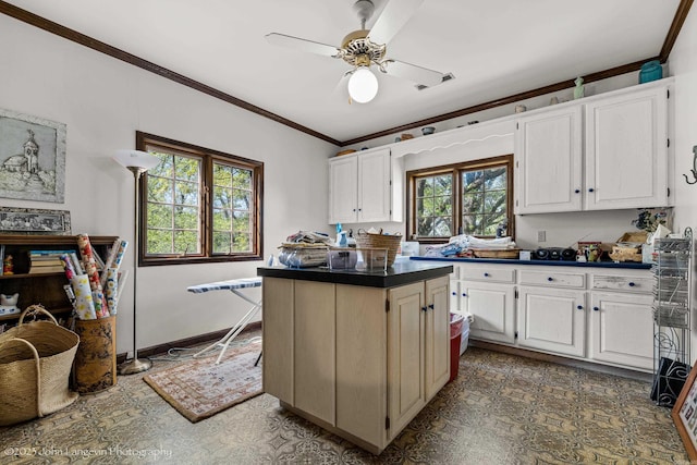 1920 Airpark Rd, Wynne, AR 72396 - kitchen featuring crown molding, a ceiling fan, white cabinetry, dark countertops, and a kitchen island