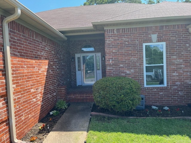 property entrance with brick siding and roof with shingles