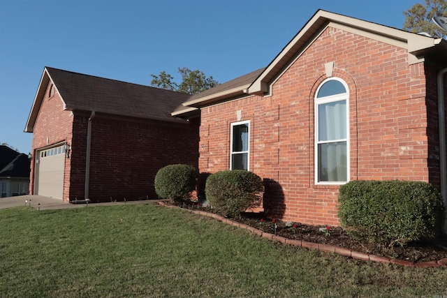 view of side of home with a yard, a garage, brick siding, and roof with shingles