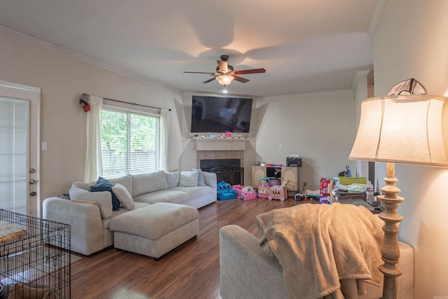 living room featuring wood finished floors, ceiling fan, crown molding, and a tiled fireplace