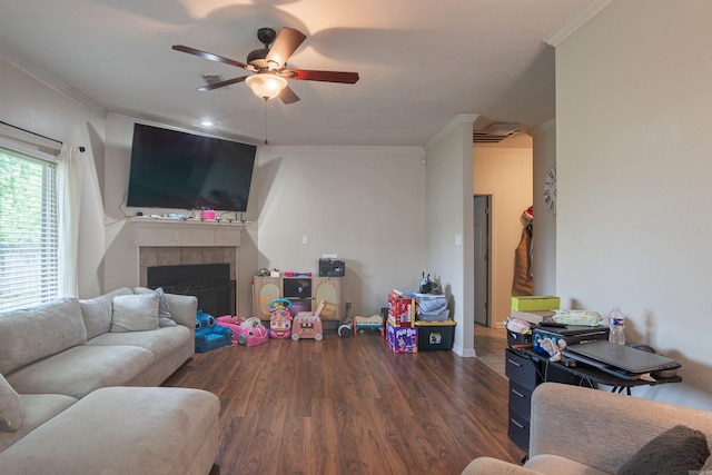living area featuring crown molding, wood finished floors, ceiling fan, a tiled fireplace, and baseboards