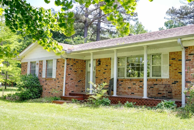 312 N E St, Harrisburg, AR 72432 - ranch-style home featuring brick siding, covered porch, a front yard, and a shingled roof