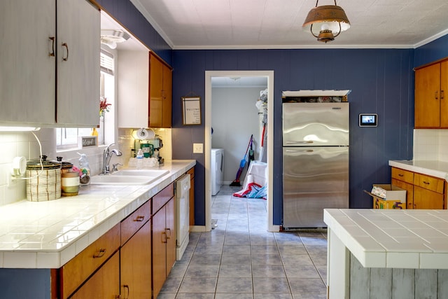 312 N E St, Harrisburg, AR 72432 - kitchen with freestanding refrigerator, a sink, washer / clothes dryer, dishwasher, and tile counters
